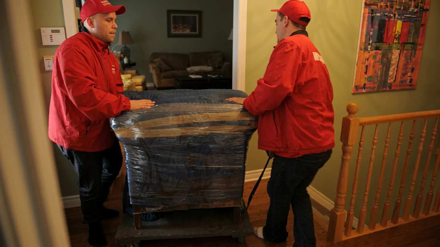 Professional movers protecting and carrying household furniture